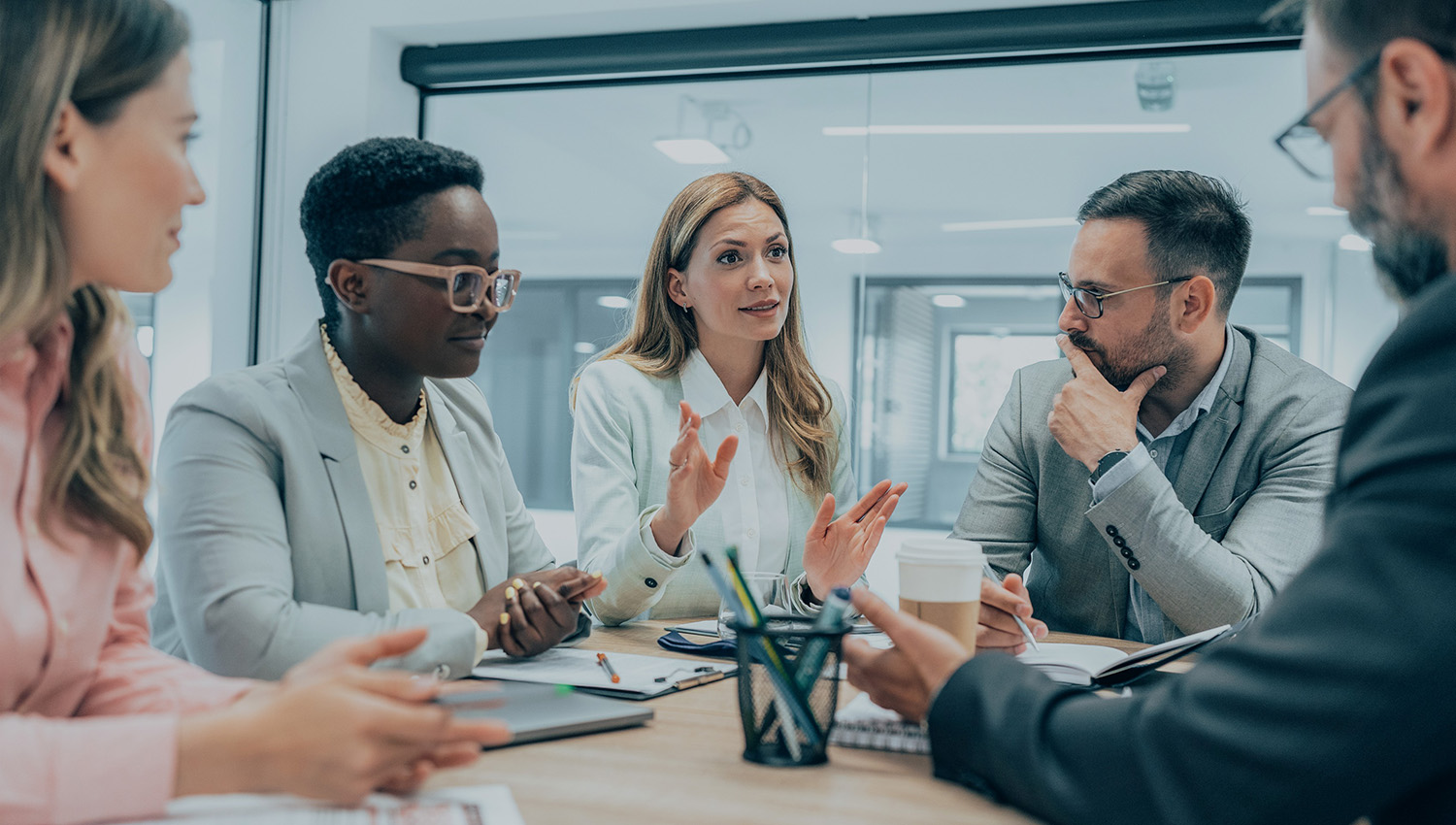 Team collaborating around a meeting table in a corporate office.